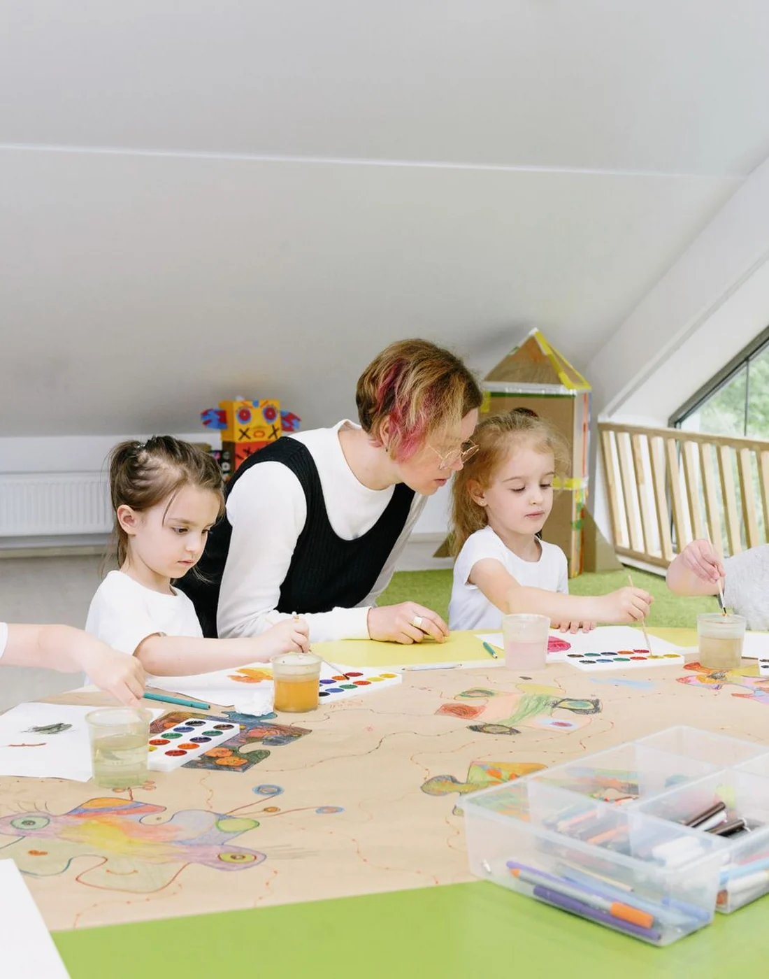 A caregiver leading an art activity with several children
