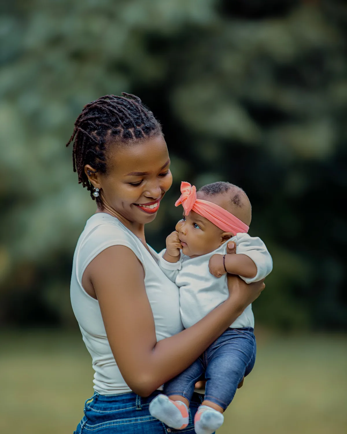 A caregiver smiling down at the baby she is holding