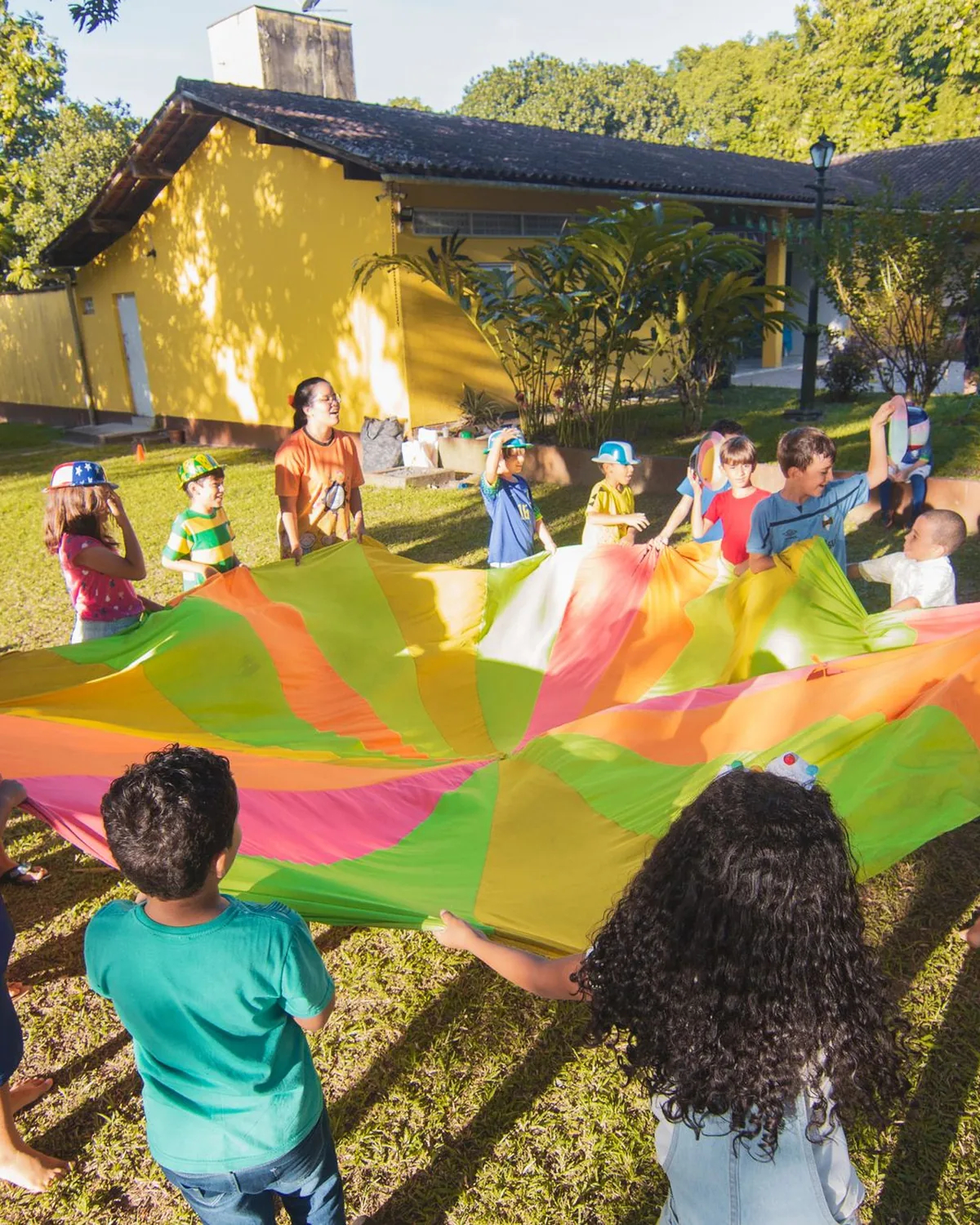 Children and adults playing with a parachute together at an outdoor event