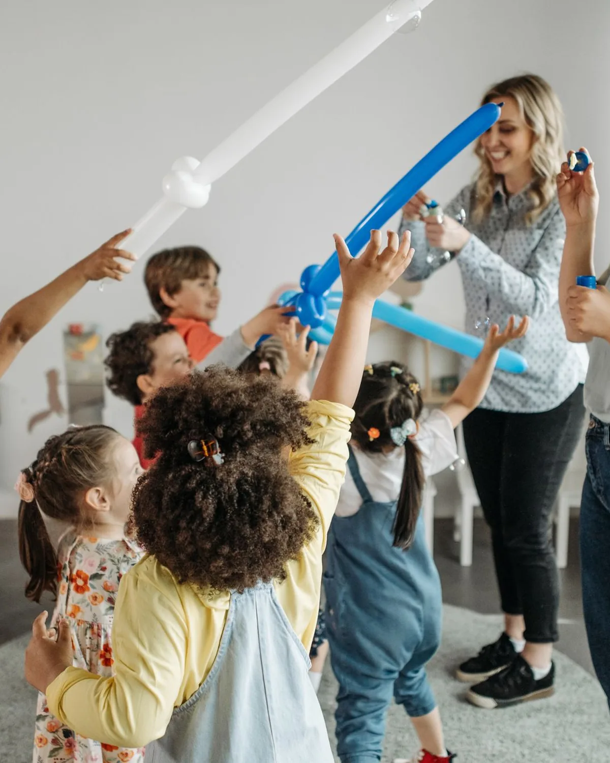 Two caregivers playing with a group of young children indoors