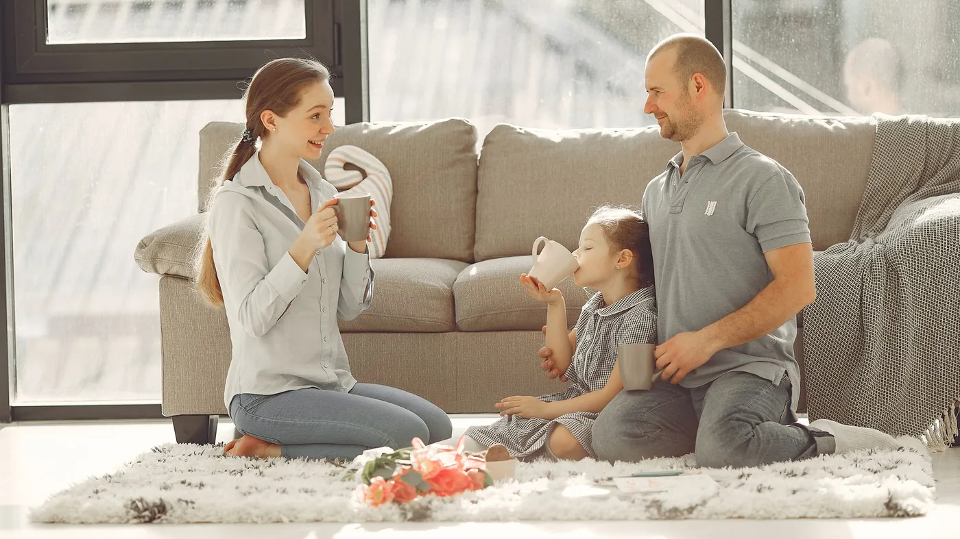 Two parents playing with their toddler on a rug at home