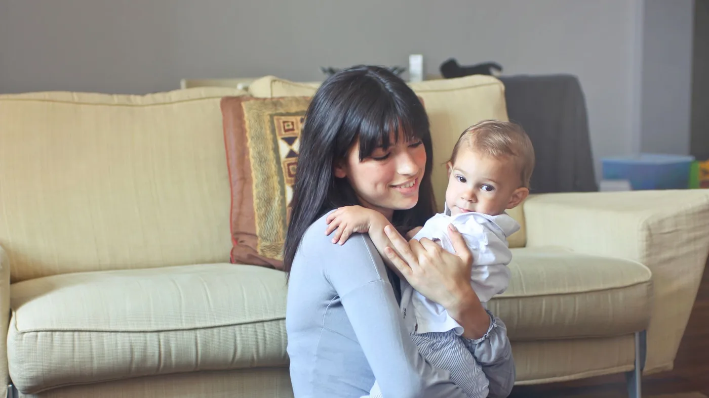 A babysitter smiling with a baby in her arms