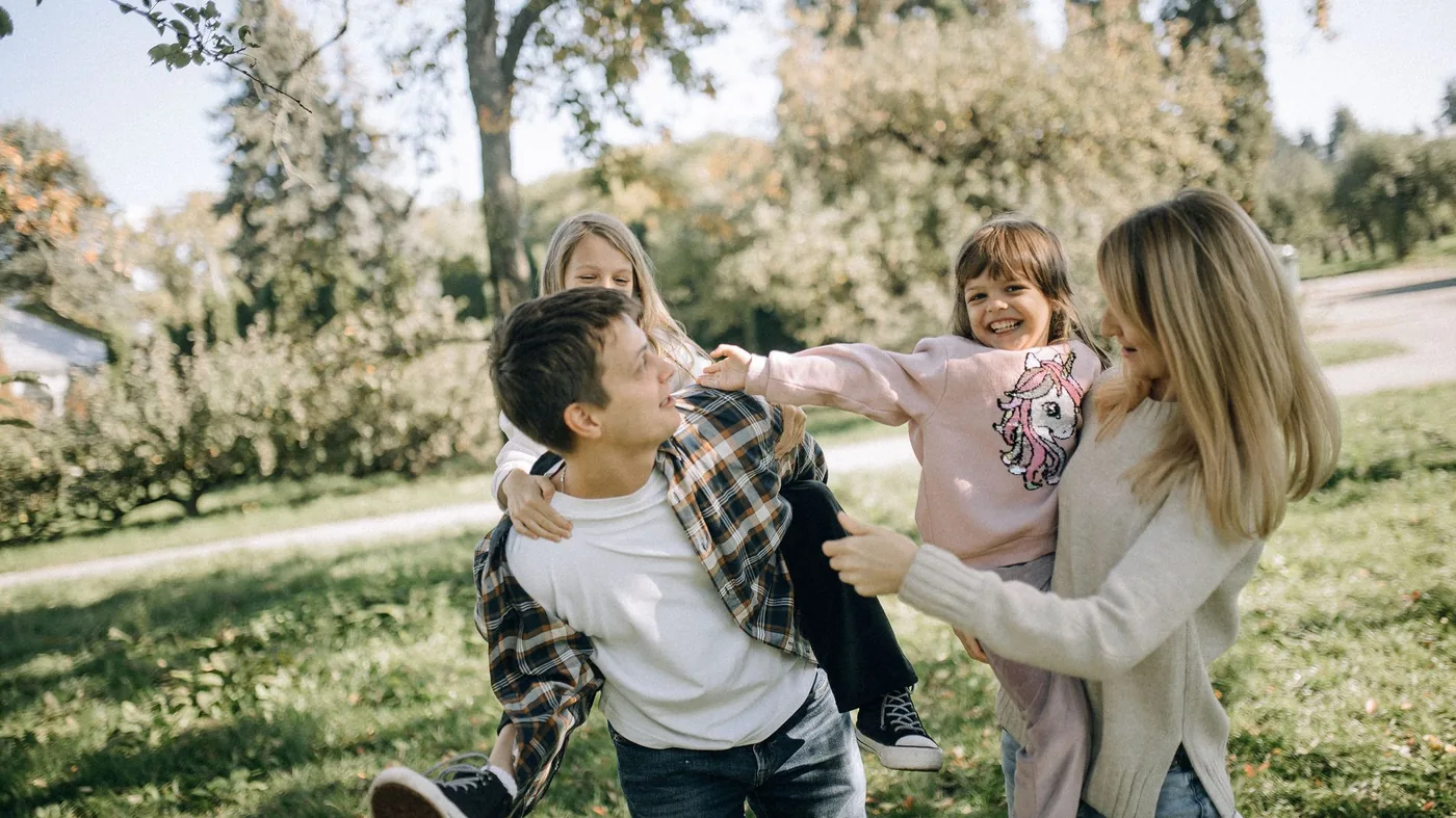 Two parents swinging their children round on the grass