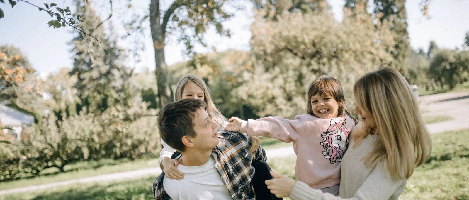 Two parents swinging their children round on the grass in a park