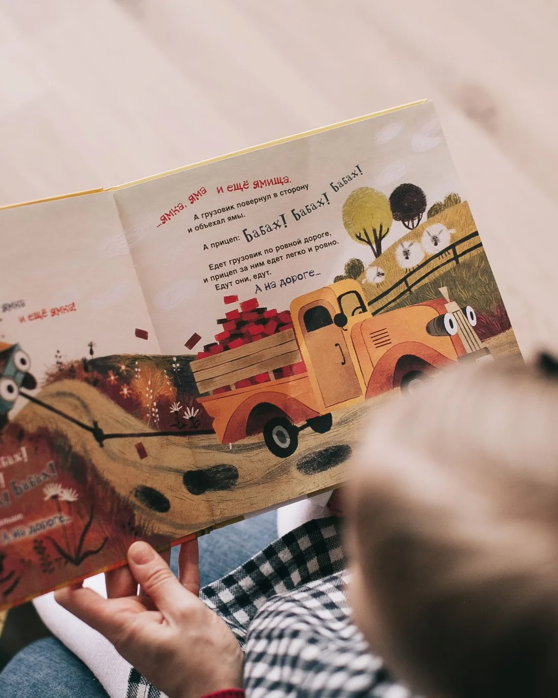 An adult and a baby looking at a picture book together