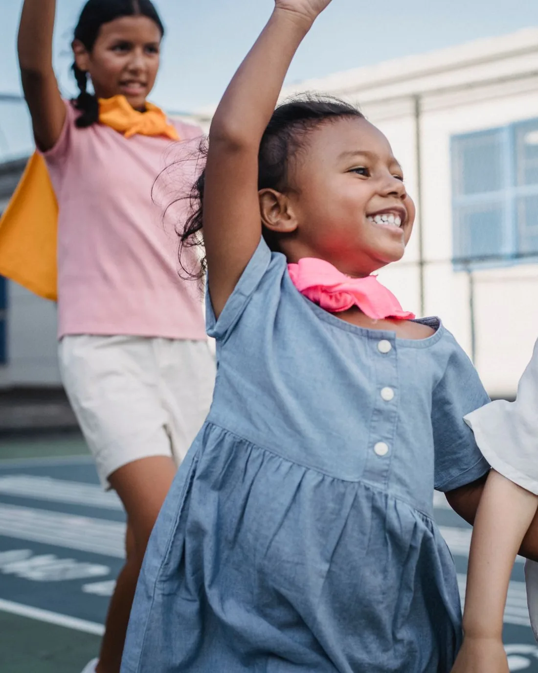 Three children dressed up for a celebration with their arms in the air